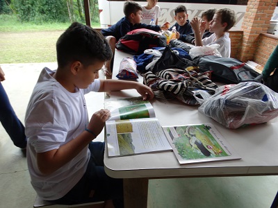 Aluno da EEB Julius Karsten Jaraguá do sul (SC) folheando a cartilha do projeto apoiado pelo CMDCA em 27/05/2019